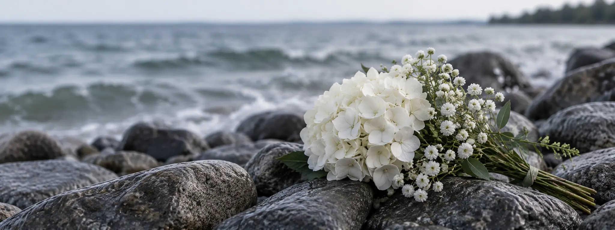White memorial flowers resting on smooth stones