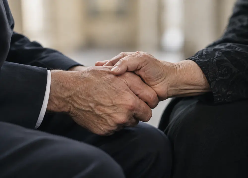 Two family members holding hands in support